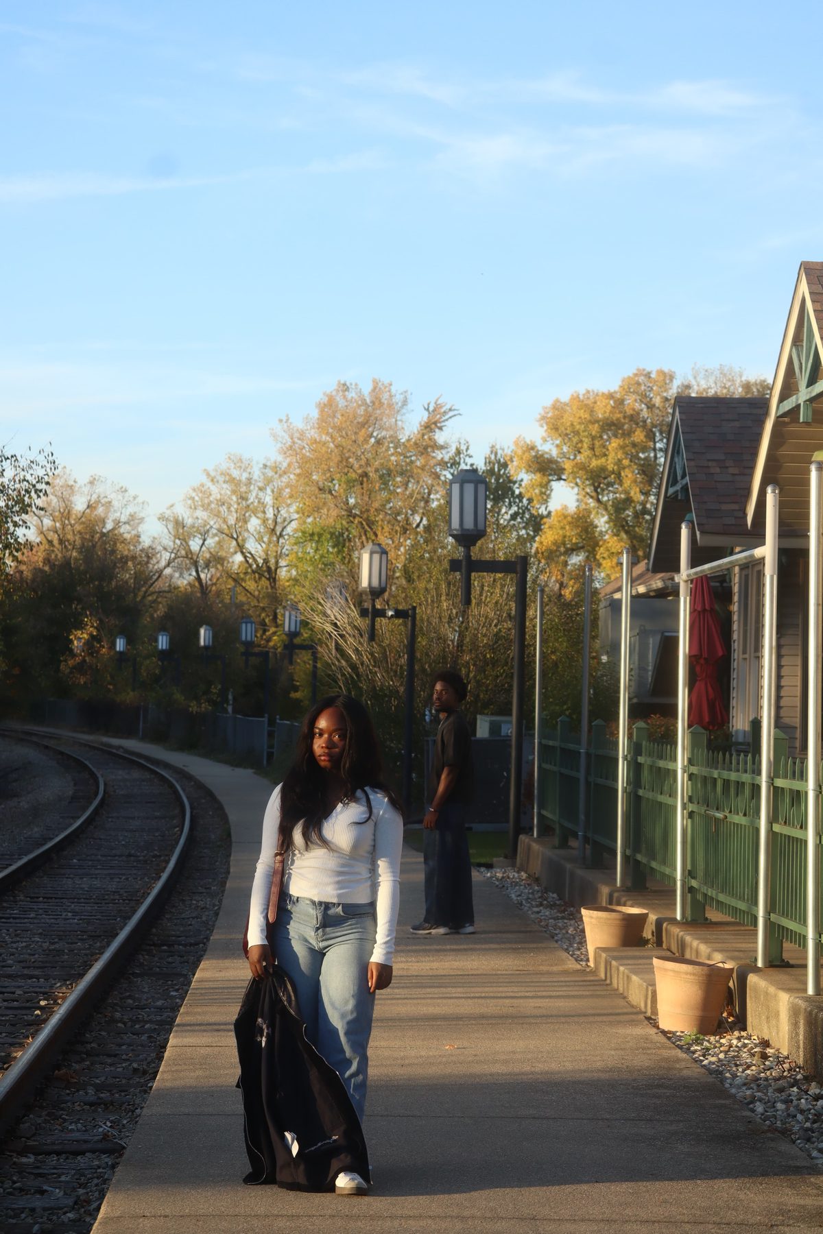 Staged Still, the woman on the platform by the rails, the man behind her