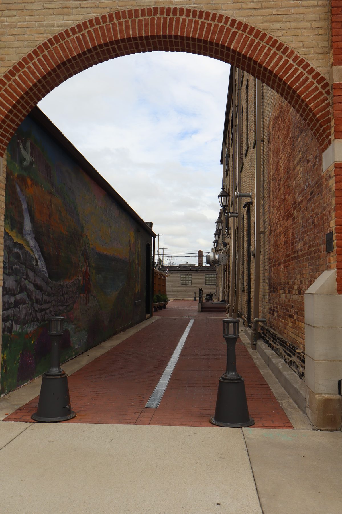 A brick archway framing a lane with a painted mural